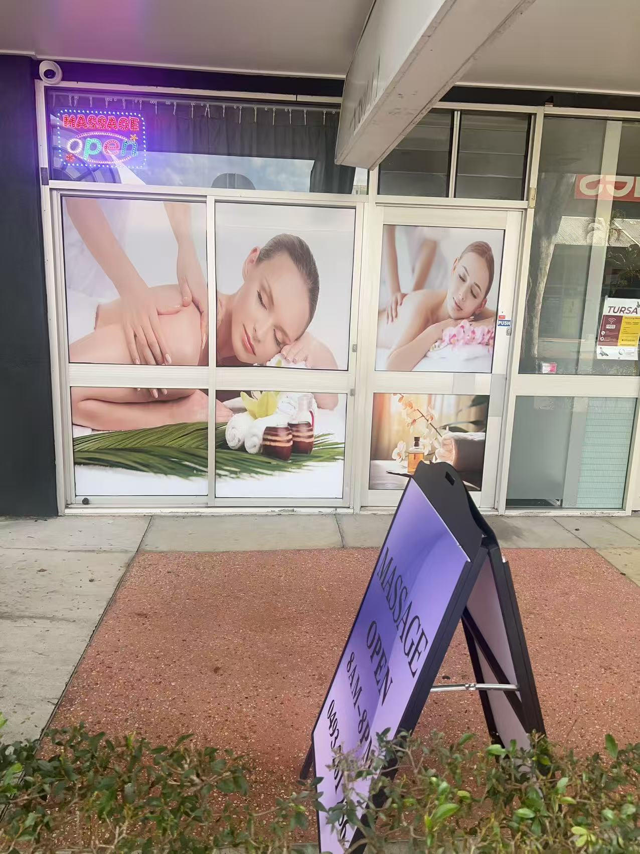 The shopfront on King St, with the lit sign in the window and the board on the footpath